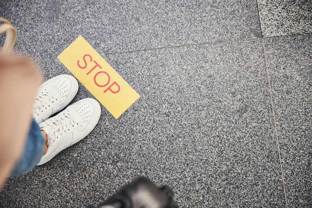 Havaalanında sarı dur işaretinin yanında duran spor ayakkabılı kadın. - Fotoğraf, Görsel