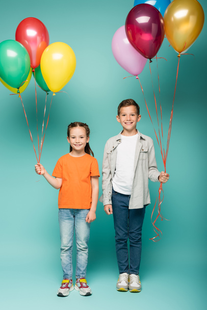 happy children holding colorful balloons on blue  - Фото, зображення