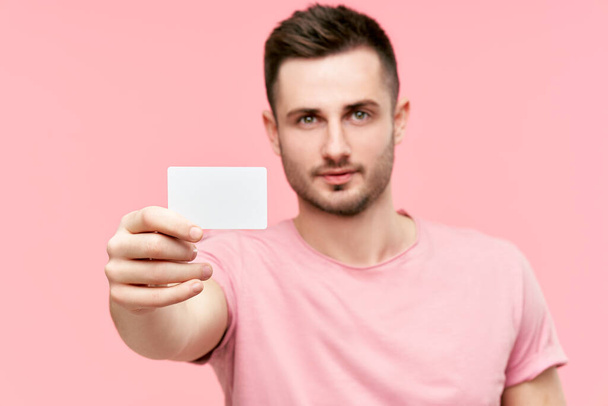 Portrét mladého muže ukazujícího kreditní kartu a hledajícího do kamery - Fotografie, Obrázek