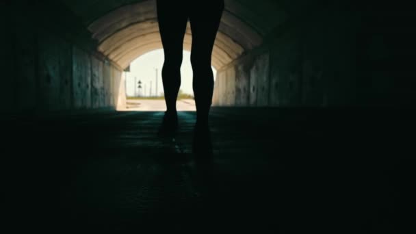 женщина бежит в тёмном туннеле, чтобы встретить свет. Силуэт женщины сзади, бегущей к свету. - Кадры, видео