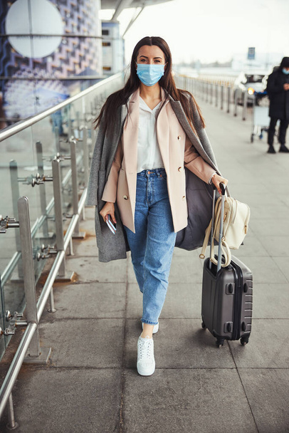 Elegáns nő orvosi maszk áll a szabadban a repülőtéren - Fotó, kép