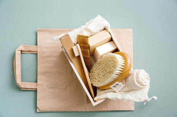 Personal care accessories made from natural materials: wooden toothbrushes, bamboo comb, organic soap, reusable cotton bags on a green background. Zero waste, green shopping, sustainable lifestyle. - Fotografie, Obrázek