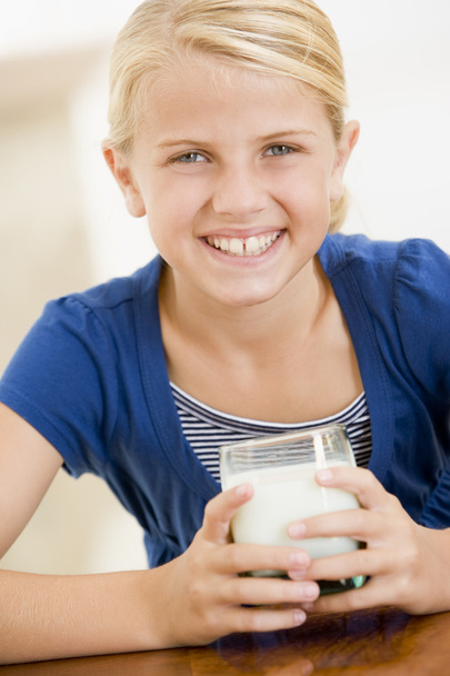 Young girl indoors drinking milk smiling - Foto, Imagen