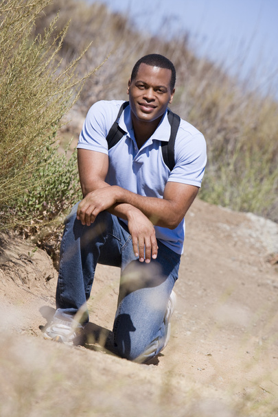 Man crouching on path to beach smiling - Фото, зображення