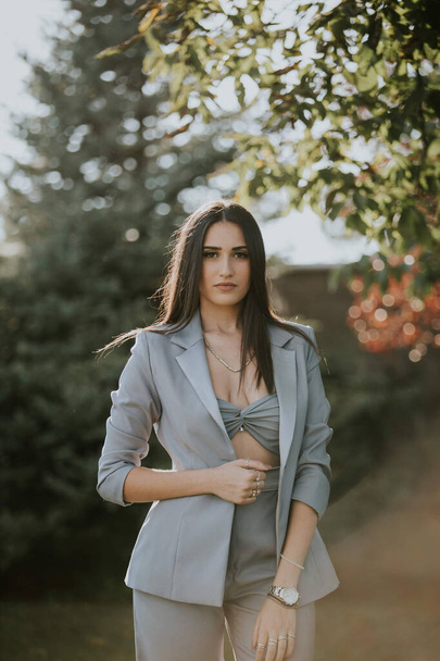 A vertical shot of a young female in a sexy gray pantsuit posing outdoors - Photo, Image