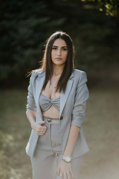 A vertical shot of a young female in a sexy gray pantsuit posing outdoors - Foto, immagini