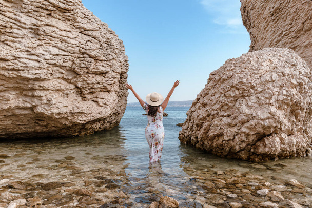 Woman in elegant long white summer dress standing on beautiful Beritnica beach with large rock formations on Pag island in Croatia. - Fotografie, Obrázek