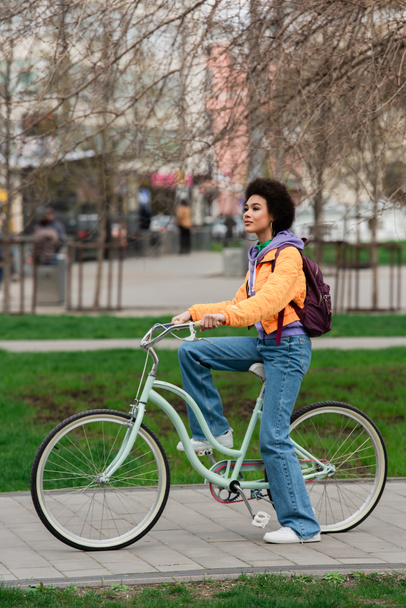 African american woman riding bicycle on urban street  - Photo, Image