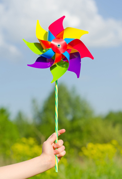 παιδί χέρι που κρατά pinwheel μπλε ουρανό. - Φωτογραφία, εικόνα