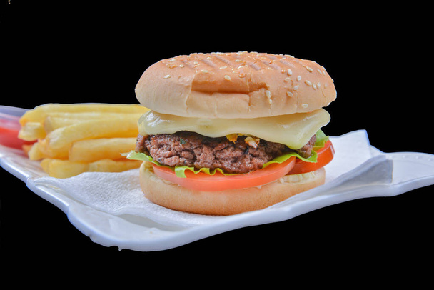 Hamburger with cheese, veggies and French fries on a black background - Photo, Image
