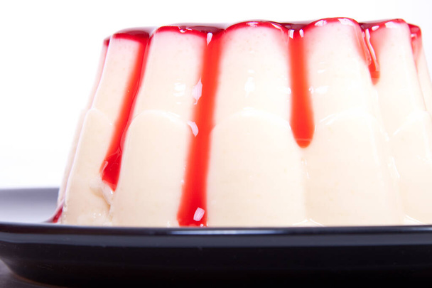 A panna cota dessert with berries on a black plate - 写真・画像