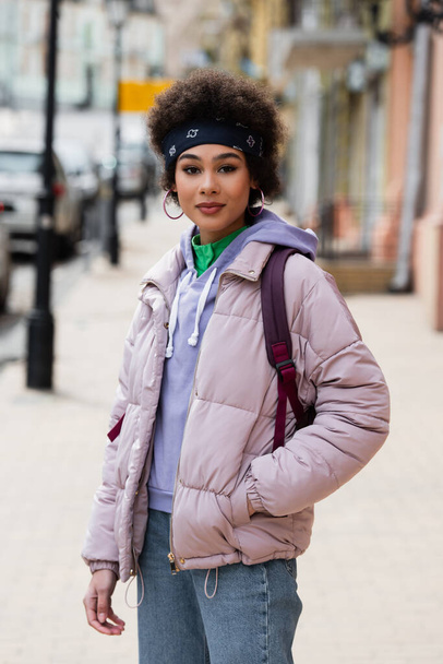 African american woman in jacket looking at camera on urban street  - Foto, Imagem
