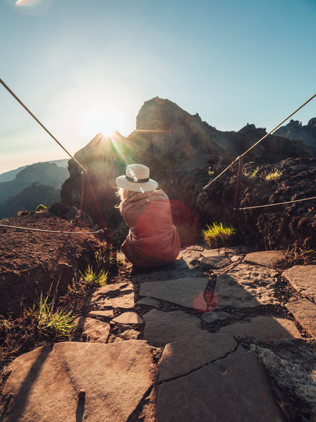 A vertical shot of a blonde woman on a trail in the mountains, enjoying the beautiful view - Photo, image