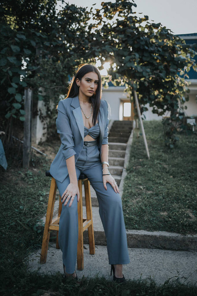 A vertical shot of a young female in a sexy gray pantsuit posing outdoors - Foto, afbeelding