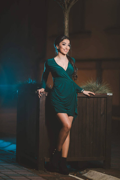 A young female from Bosnia and Herzegovina in a green elegant dress leaning on a big wooden pot - Photo, Image