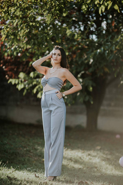 A vertical shot of a young female in a sexy gray pantsuit posing outdoors - Fotoğraf, Görsel