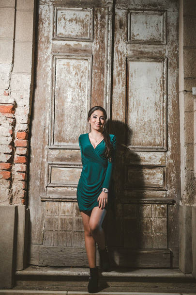 A vertical shot of a young elegant female in a green dress posing outdoors - Zdjęcie, obraz