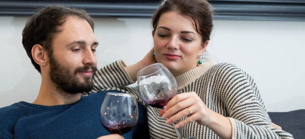 Młoda i szczęśliwa para pijąca wino i relaksująca się w domu - Zdjęcie, obraz
