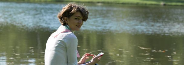 Nuori nainen puistossa puhuu matkapuhelimella. Söpö tyttö muotokuva ranskalainen tyyli. - Valokuva, kuva