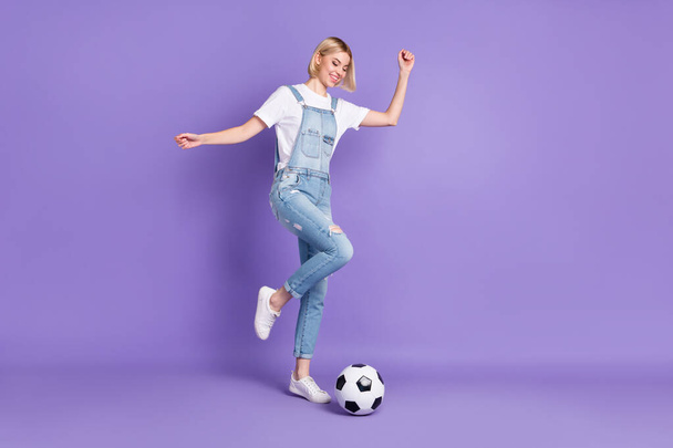 Full length profile side photo of young girl happy positive smile play kick ball game match isolated over purple color background - Фото, изображение