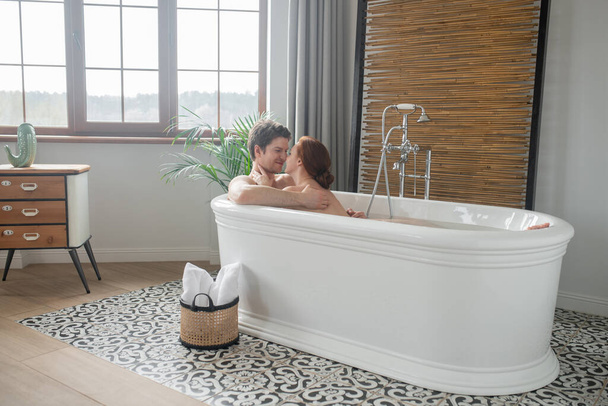 A man and a woman having a bath together and looking enjoyed - Foto, afbeelding