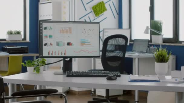 Számítógép üres munkahelyen grafikonokkal a képernyőn és kerekesszékkel - Felvétel, videó