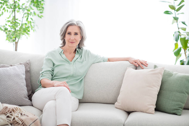 Photo of calm peaceful pretty old woman sit sofa good mood wekend wear casual outfit inside house home indoors - Фото, зображення