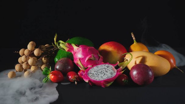 Exotic fruits in the white smoke on black - Photo, Image