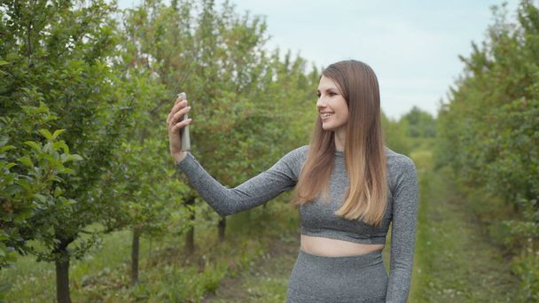 Сучасна спортивна жінка фотографує природу смартфона, записуючи відео блог. Спортивний відеоблог. Відеоблог спортсмена. Дівчина-блогер вказує на природу камери
 - Фото, зображення