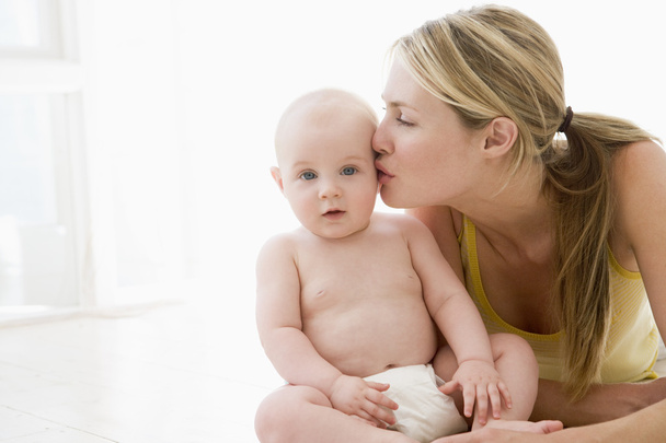 Mother kissing baby indoors - Fotó, kép