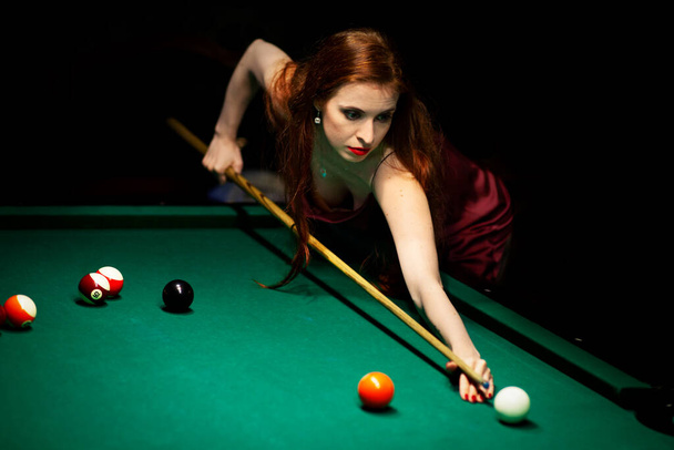 Woman aiming for the billiard table in dark room - Fotografie, Obrázek
