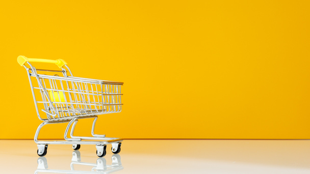 empty shopping cart. Minimum concept. Yellow and white background. place for a note  - Photo, Image