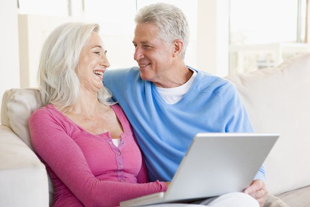 Couple in living room with laptop smiling - Photo, Image