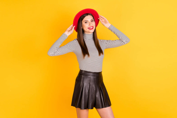 Photo of young cheerful girl happy positive smile hands touch retro hat wear black skirt isolated over yellow color background - Foto, imagen