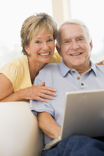 Couple in living room with laptop smiling - Foto, immagini