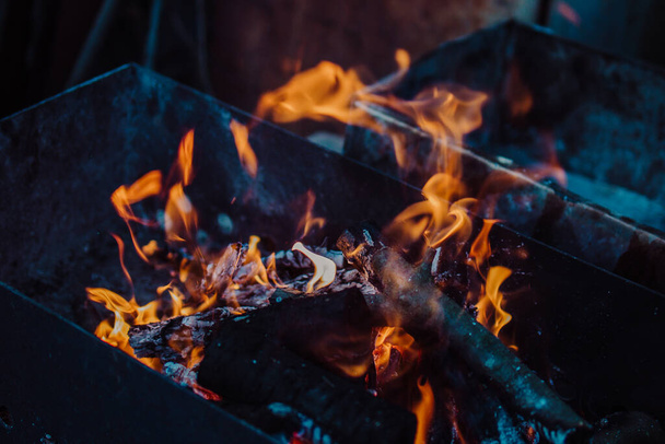brandend brandhout in de grill in donkere, donkere kleuren. - Foto, afbeelding