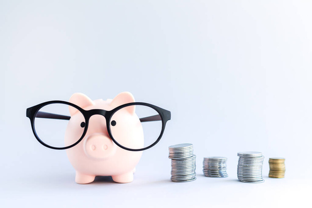 Piggy banco ao lado de pilhas de moedas em fundo cinza. Conceito de poupança e investimento - Foto, Imagem