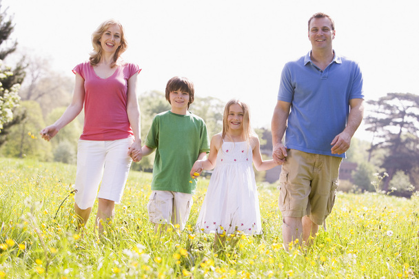 Family walking outdoors holding flower smiling - Foto, Bild