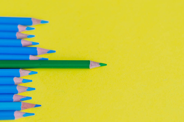 Keskinleştirilmiş mavi kalemler ve sarı arka planda bir yeşil kalem. Okul konsepti. - Fotoğraf, Görsel
