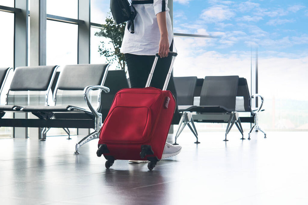 žena cestovatel prochází letištní salonek přímo k obloze; nohy a kufr zblízka - Fotografie, Obrázek
