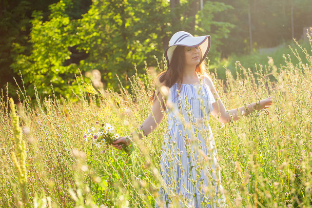 Young woman picking flowers in the meadow in summer evening - Photo, Image