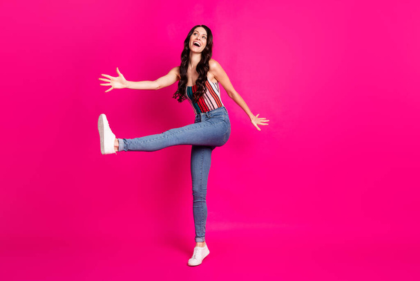 Full size profile photo of optimistic cute brunette lady dance wear top jeans sneakers look empty space isolated on vivid pink background - Foto, immagini
