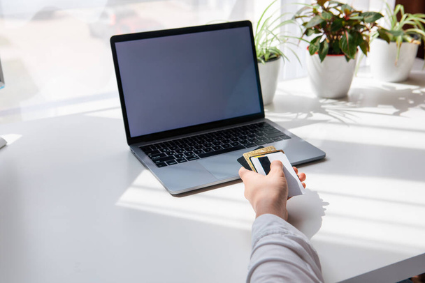 рука держит скамейку ноутбука кредитной карты с белым экраном на заднем плане покупок онлайн - Фото, изображение