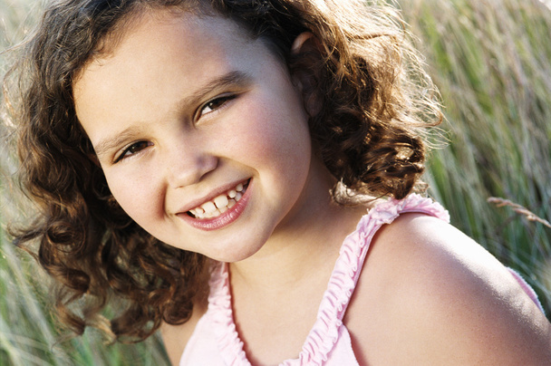 Young girl sitting outdoors smiling - Foto, imagen