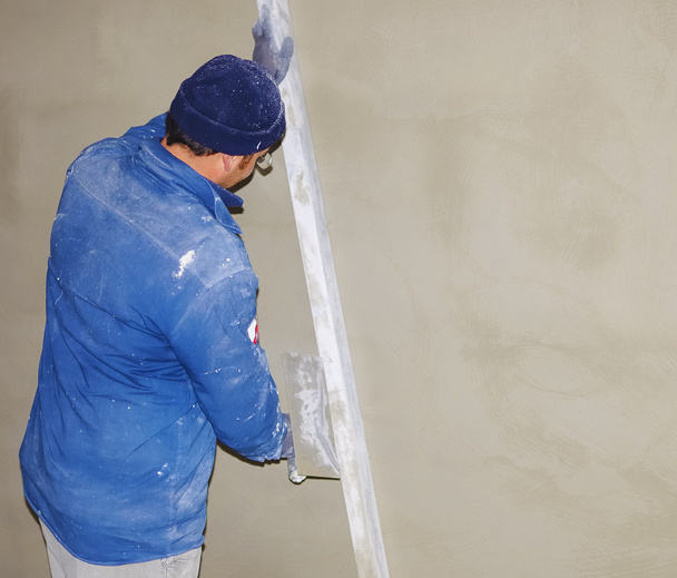 Trabajador realiza capa de cemento mortero yeso interior
 - Foto, Imagen
