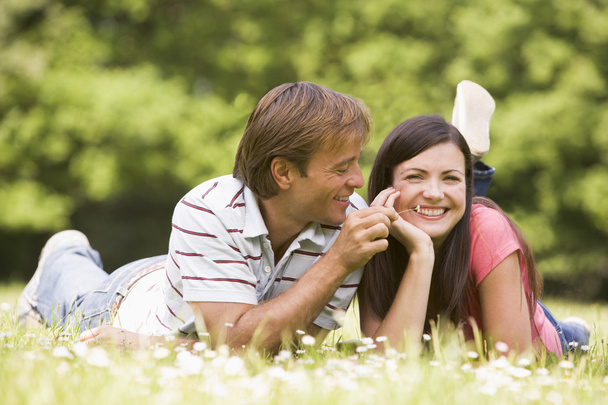 Couple lying outdoors with flower smiling - Foto, immagini