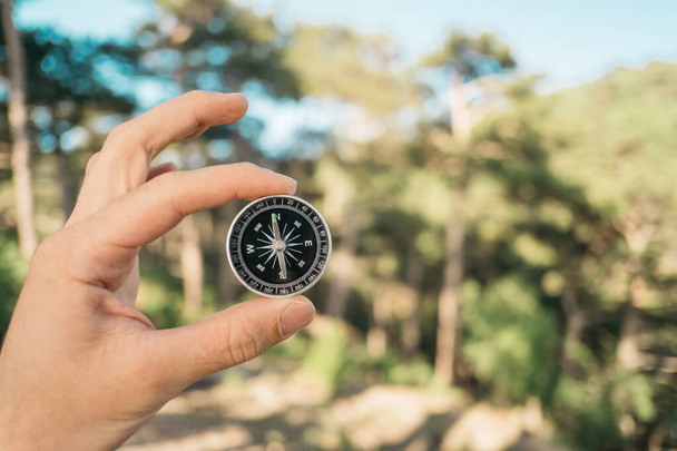 Man holds a compass in his hand in the forest. - Foto, Bild
