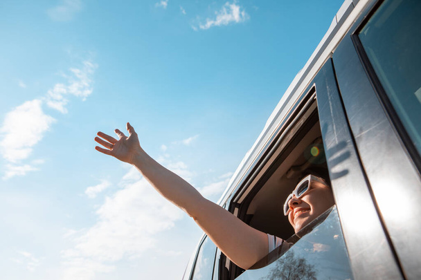 Kadın gülen suratla arabadan dışarı çıktı. Güneşli bir gün. mavi gökyüzü - Fotoğraf, Görsel