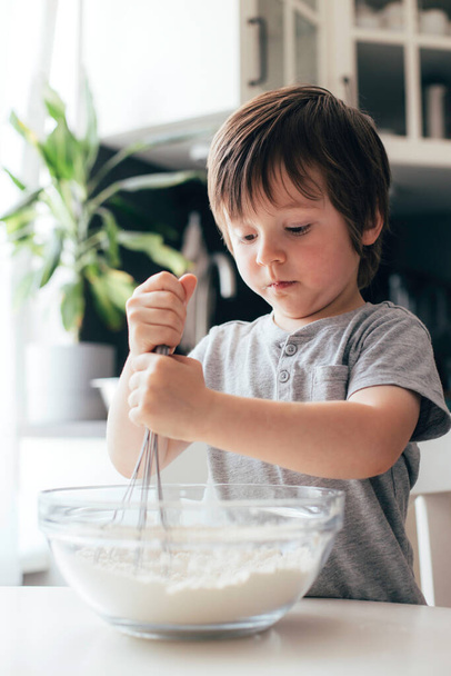 Adorable cheerful boy, Toddler kneads dough in the kitchen. Children cat dough at home. Real life moments - Fotoğraf, Görsel