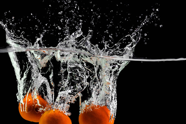 three tangerines fall into the water on a black background, copy space - Valokuva, kuva